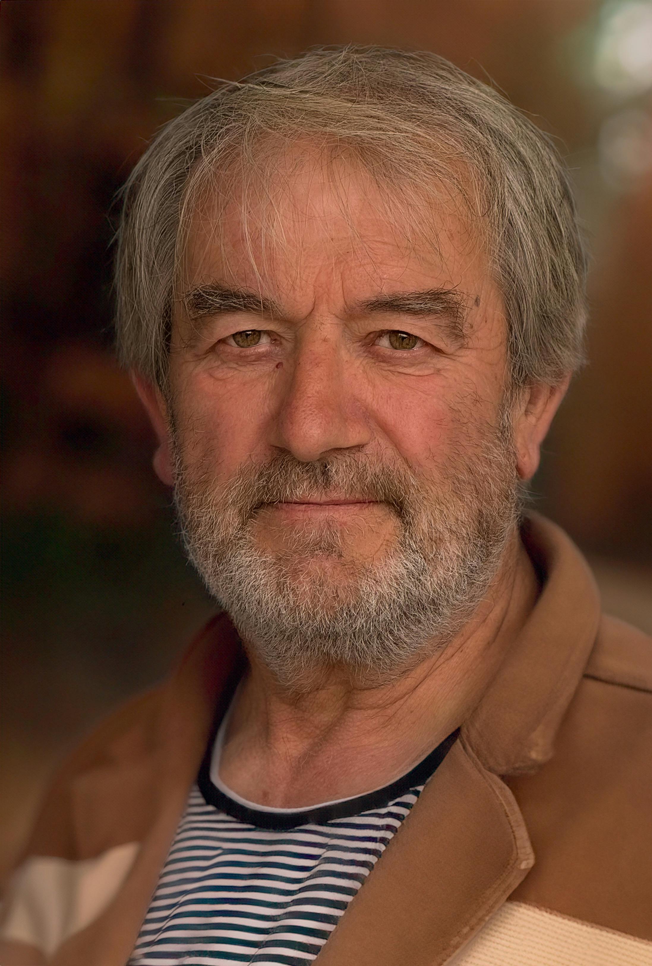 A candid portrait of a senior man with a thoughtful expression outdoors.