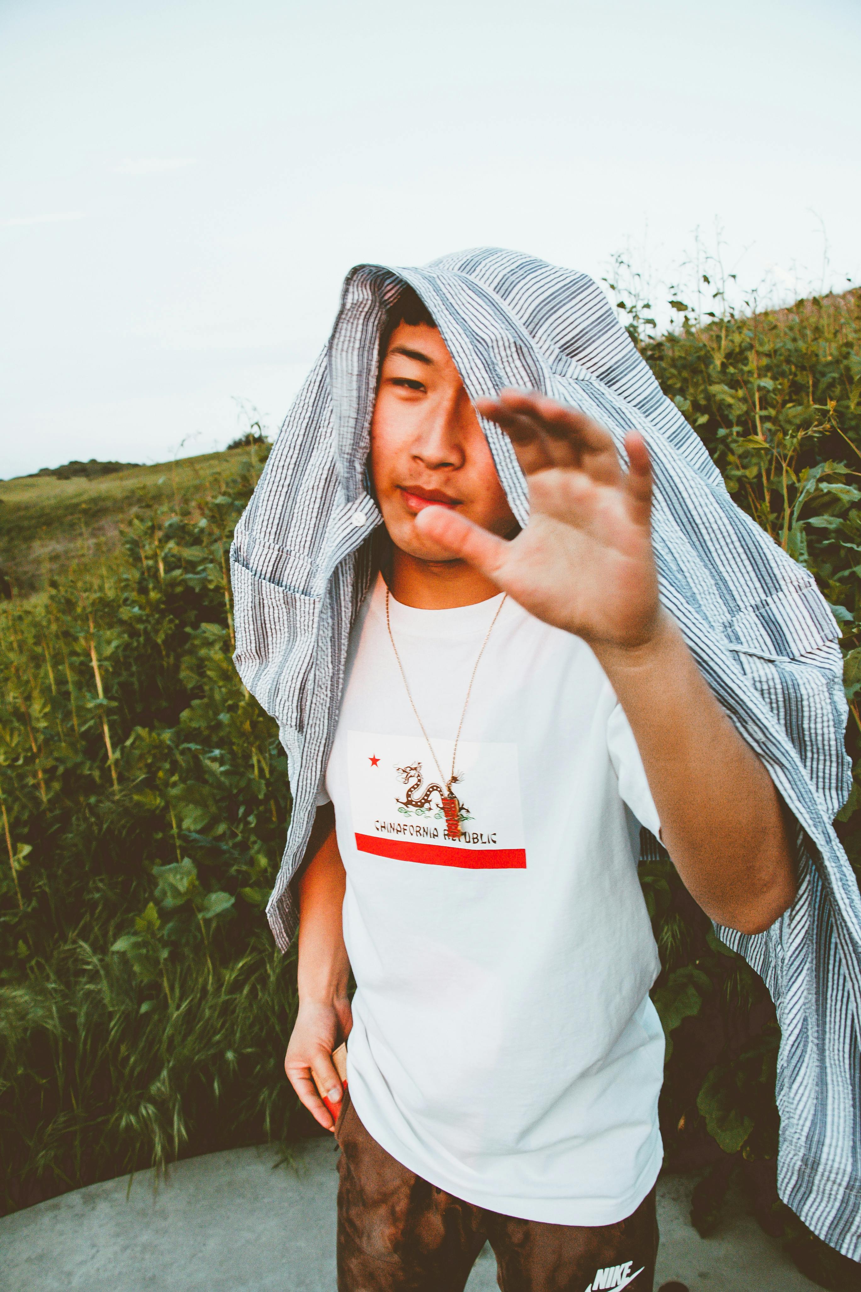 一个年轻人随意打扮，头上披着件衬衫，在户外享受夏日时光