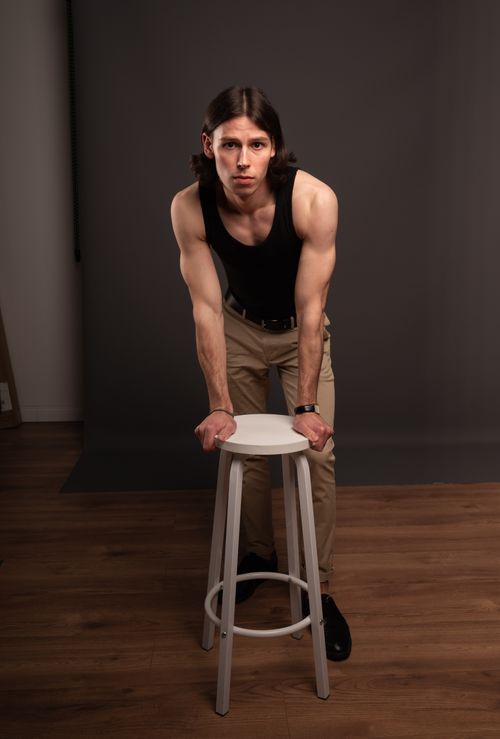 Free A confident male model in a black tank top poses with intensity in a professional studio setting. Stock Photo