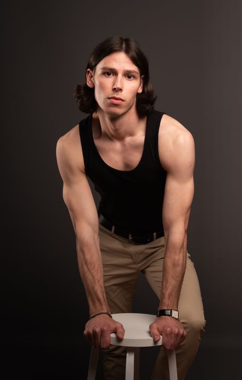 Free Portrait of a young man in a black tank top posing confidently in a studio setting. Stock Photo