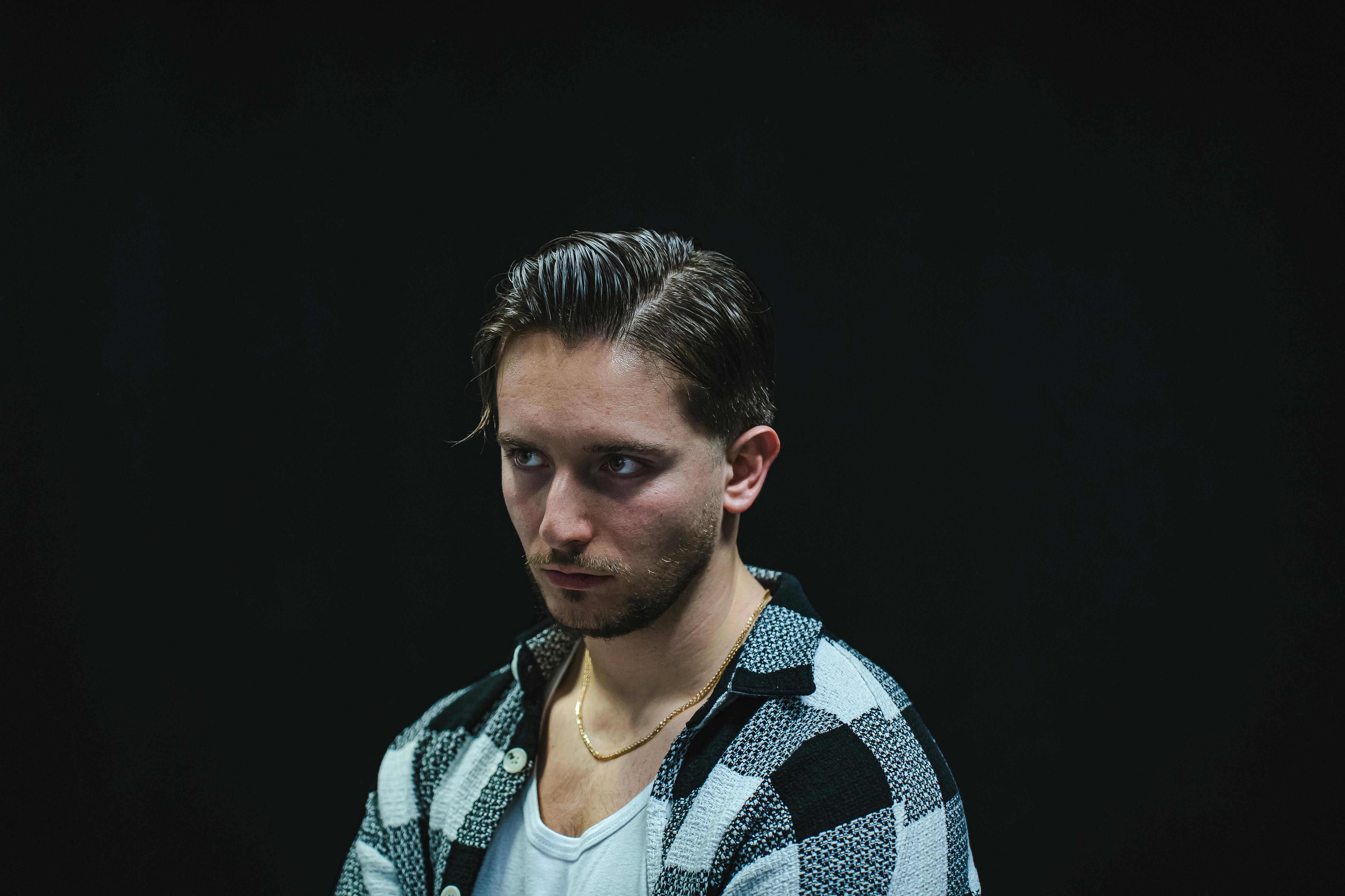 Zadarmo Dramatický štúdiový portrét muža v kockovanej košeli na tmavom pozadí. Fotka z fotobanky
