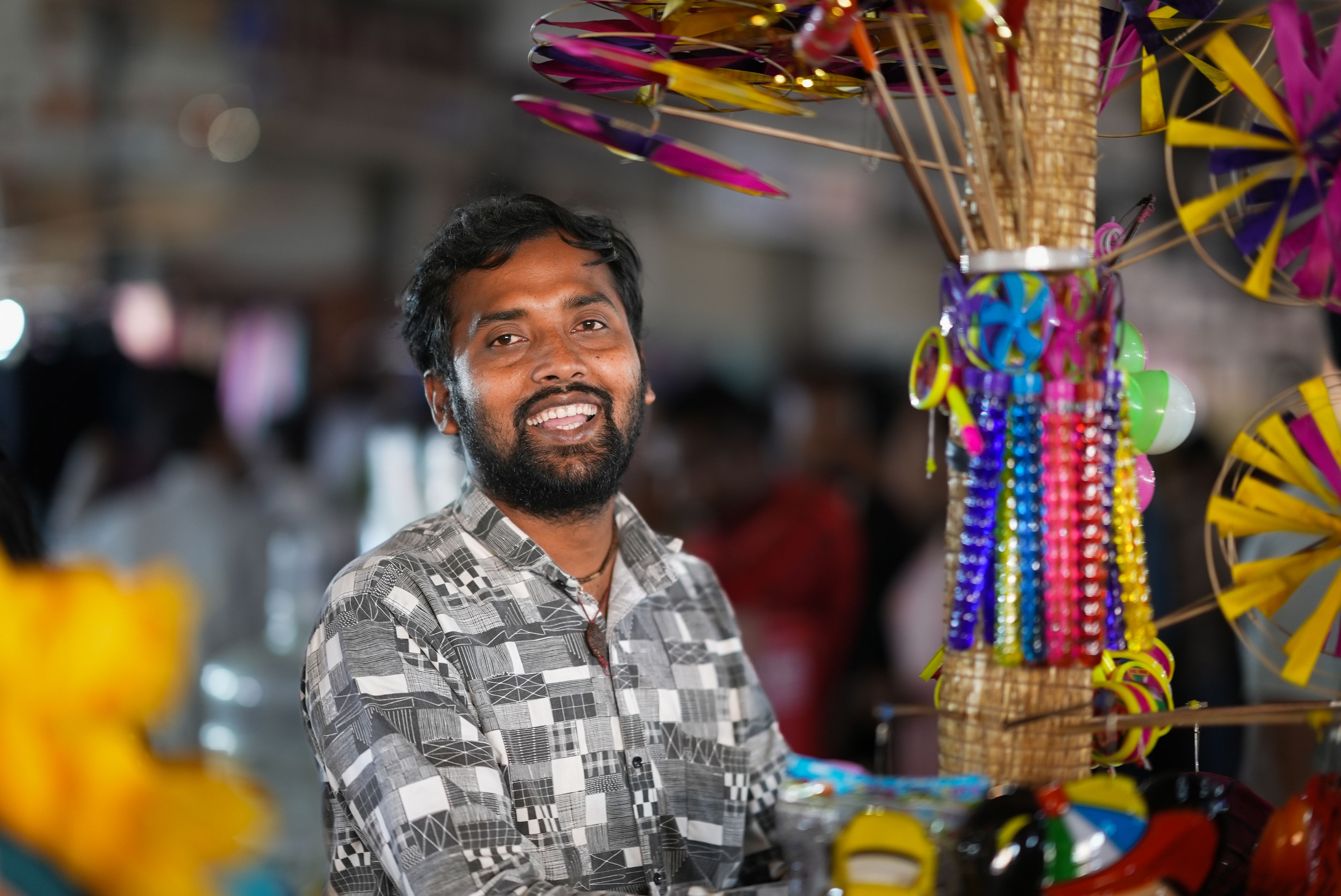 Smiling Vendor with Colorful Pinwheels · Free Stock Photo