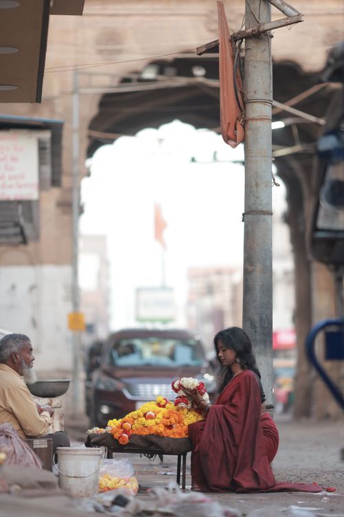 Free Woman sells vibrant flowers in bustling street market, rich culture and tradition. Stock Photo