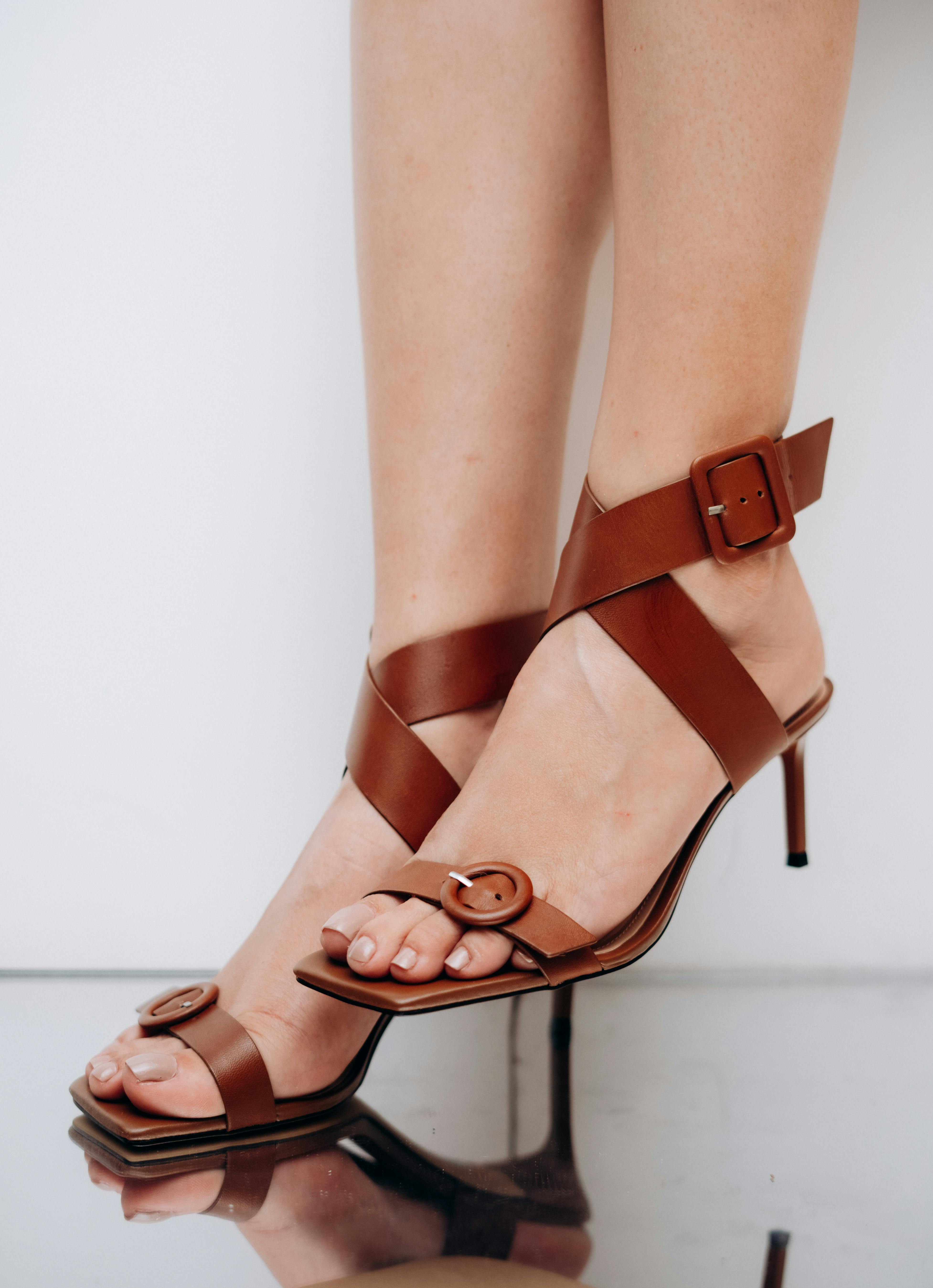 Close-up of brown leather high-heeled sandals on female feet, showcasing elegance and style.