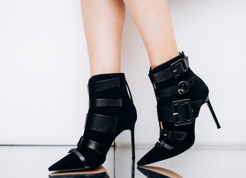 Fashionable black high-heeled ankle boots with stylish buckle straps showcase chic footwear design.