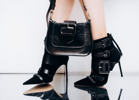 Chic black stiletto heels paired with a stylish handbag, showcasing modern fashion elegance.