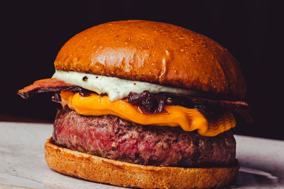 Delicious close-up of a gourmet cheeseburger with bacon and cheddar.