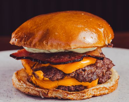 Close-up of a juicy cheeseburger with bacon, cheese, and sauce on a bun.