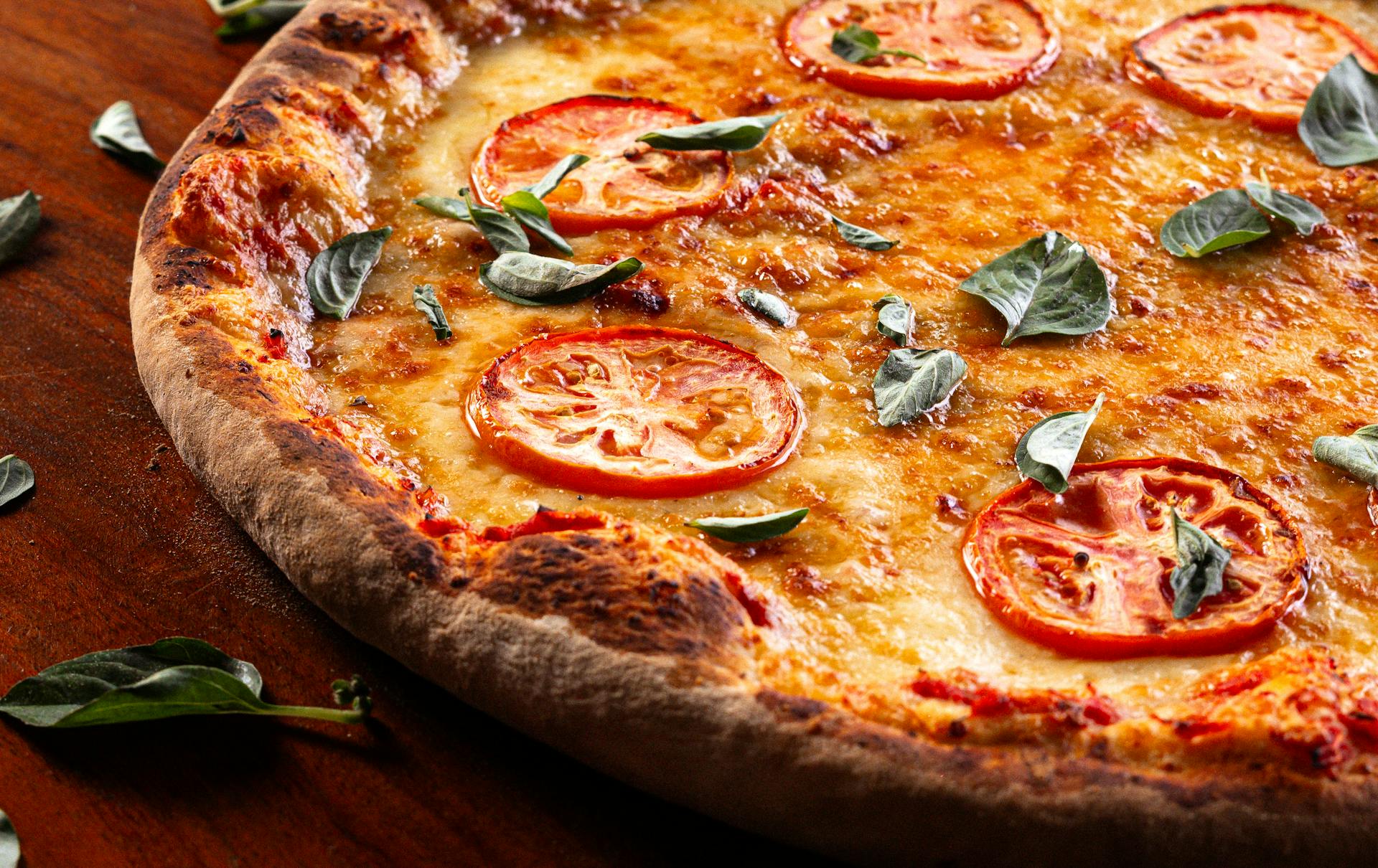 Close-up view of a Margherita pizza topped with fresh tomato slices and basil leaves.