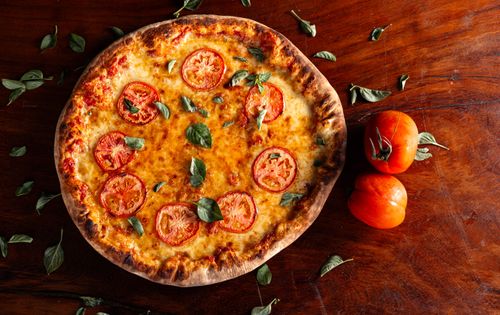 Free Tasty Margherita pizza topped with fresh tomatoes and basil leaves. Stock Photo