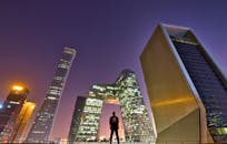 黄昏时分，一个人影俯瞰着北京的天际线，聚焦于现代建筑