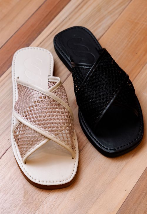 Free Elegant mesh sandals in beige and black placed on a wooden floor, showcasing modern footwear design. Stock Photo