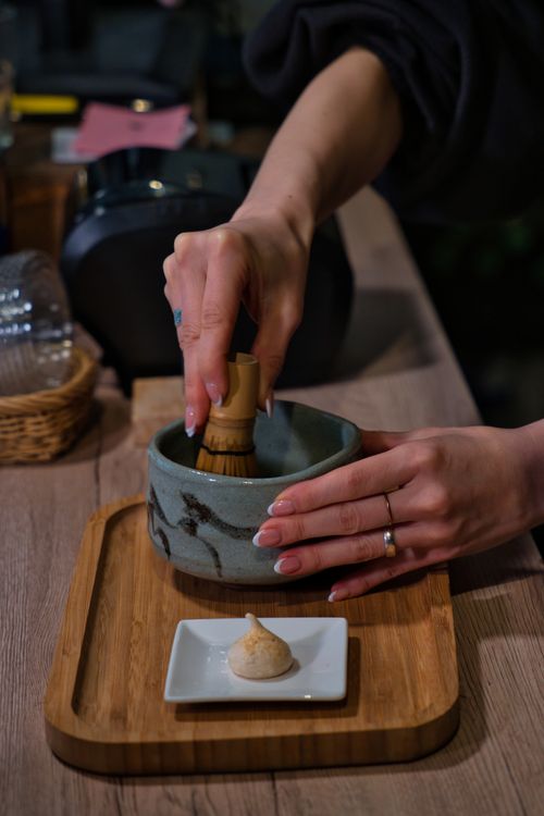 Free Hands preparing traditional matcha tea with whisk in a Berlin setting, emphasizing ritual and culture. Stock Photo