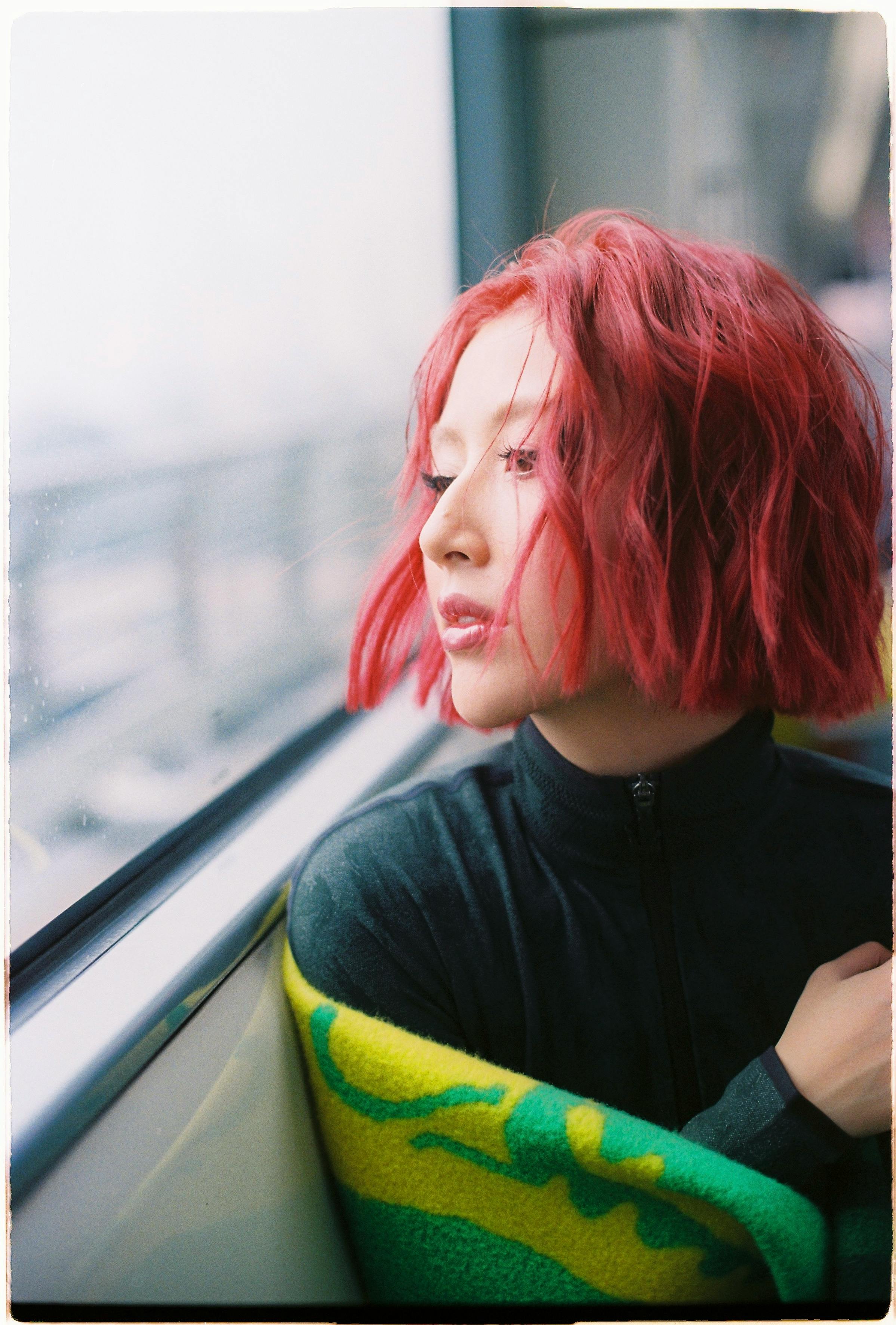 Red-haired woman gazing thoughtfully out the window during train journey.