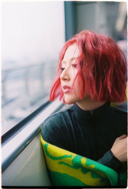 Red-haired woman gazing thoughtfully out the window during train journey.