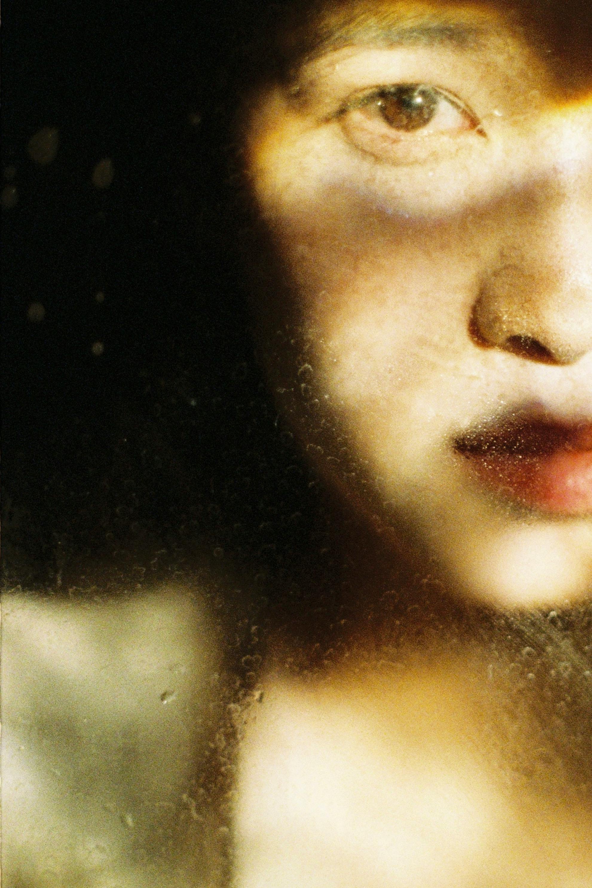 Close-up artistic portrait with dramatic light and shadow on face.