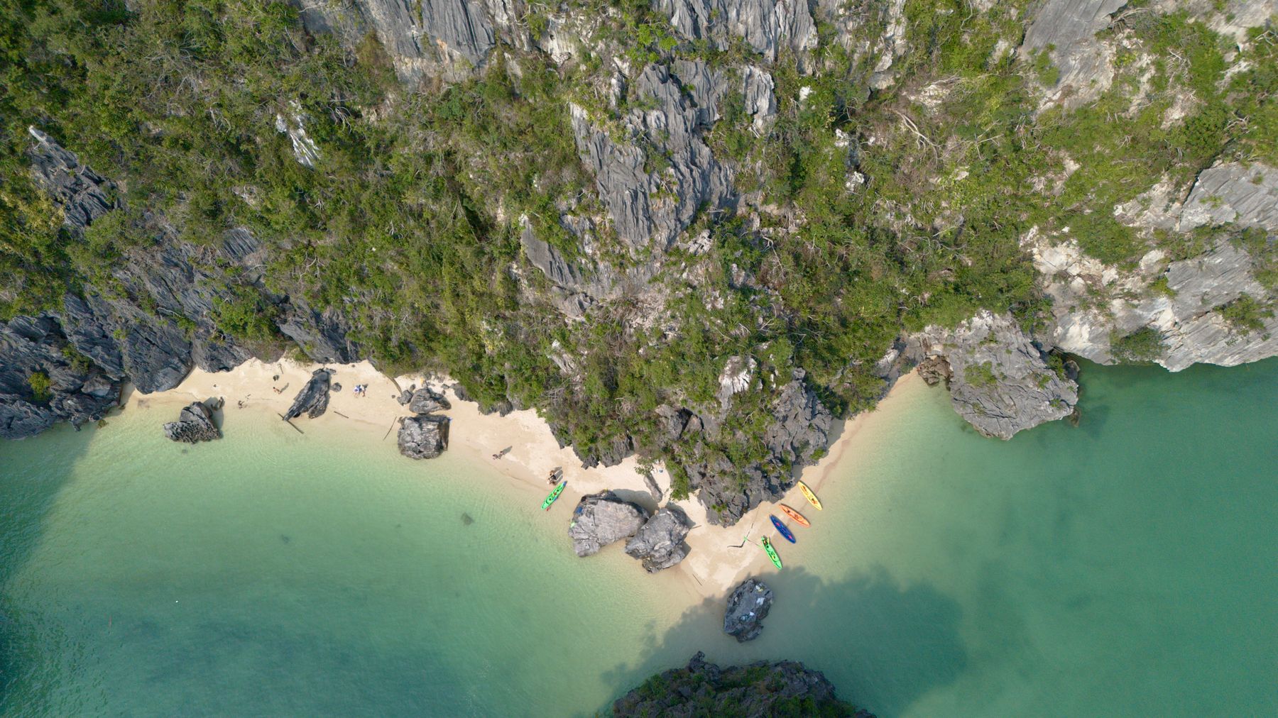 Aerial shot of a remote tropical beach with kayaks and lush greenery.