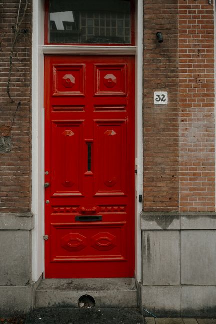 Red door on a charming Amsterdam brick building facade.