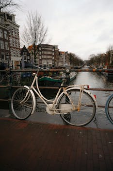 A vintage bicycle parked by an Amsterdam canal, capturing iconic Dutch scenery.