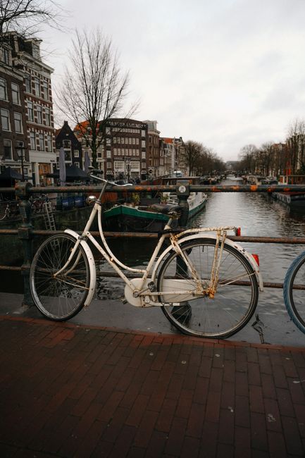 A vintage bicycle parked by an Amsterdam canal, capturing iconic Dutch scenery.