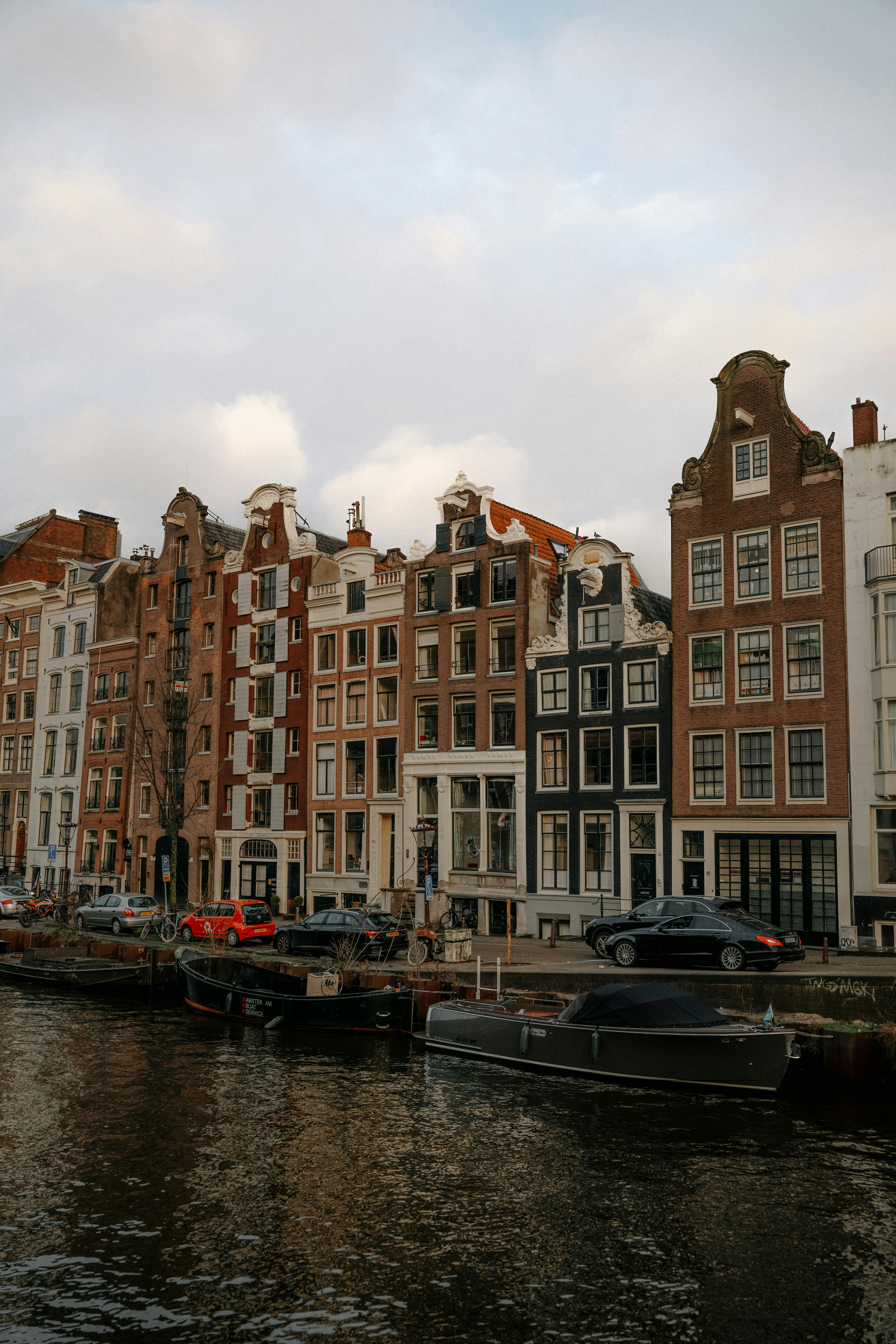 Picturesque view of Amsterdam canal houses reflecting historical Dutch architecture at sunset.