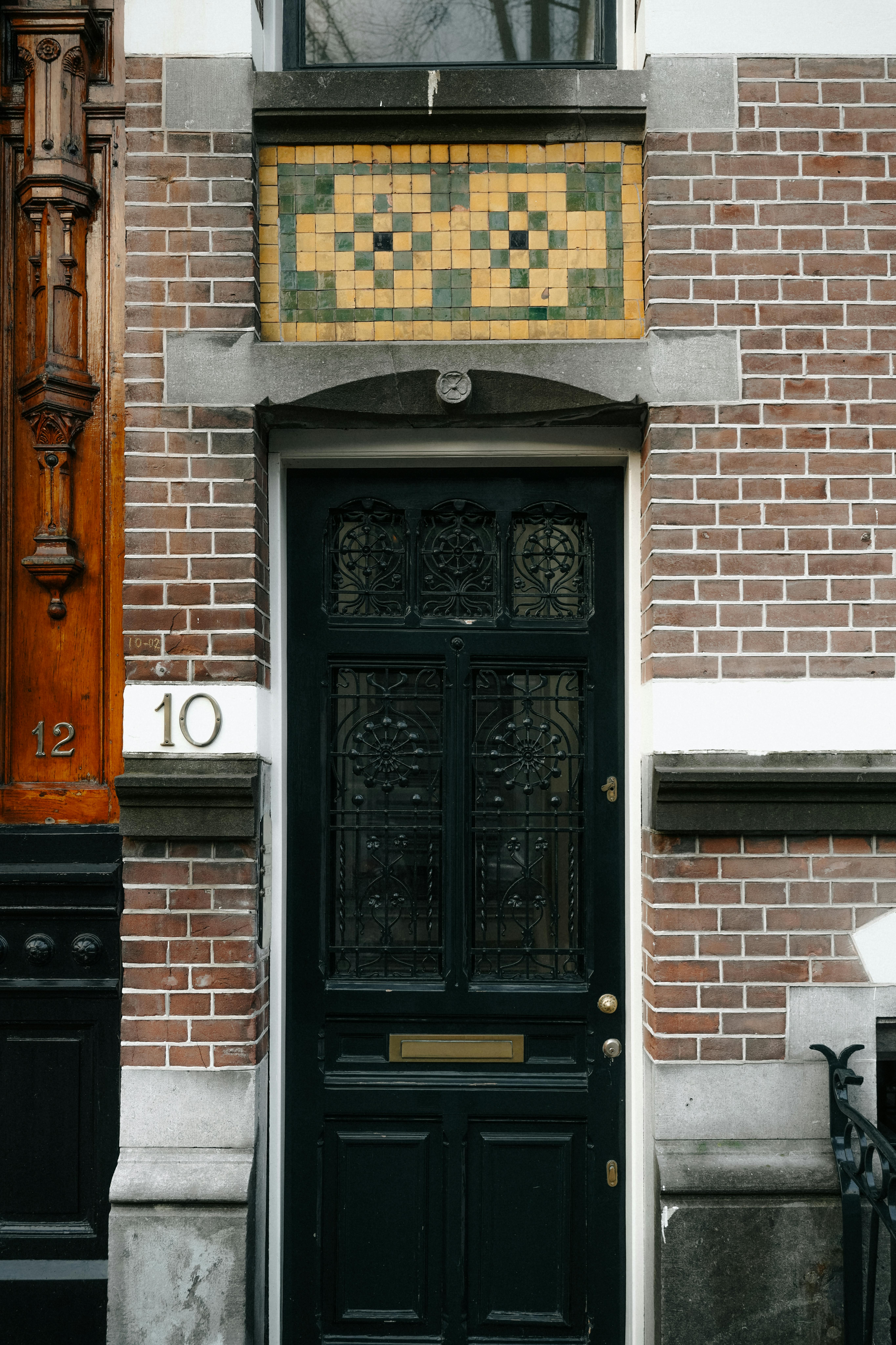 Close-up of an intricately designed door on a historic Amsterdam building with brick facade.