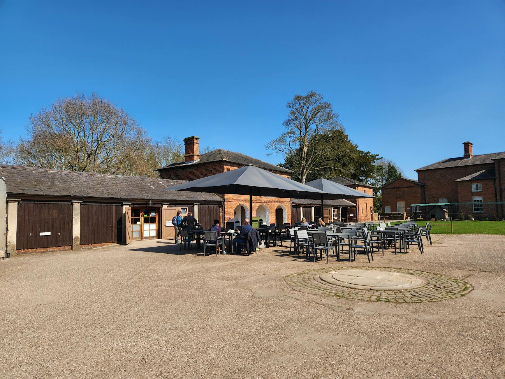 Best outdoor restaurants London 2025: Cozy cafe with outdoor seating at a historic brick building under a clear blue sky.