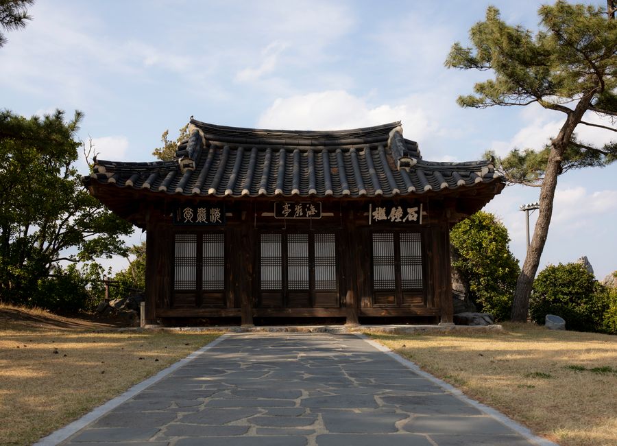 Captivating view of a traditional Korean Hanok surrounded by lush greenery and clear skies.