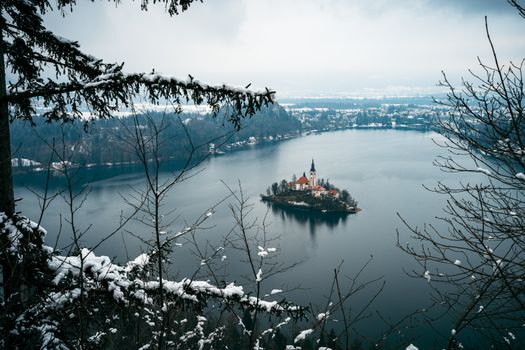 Snowy landscape with a view of Lake Bled and its iconic church on an island.