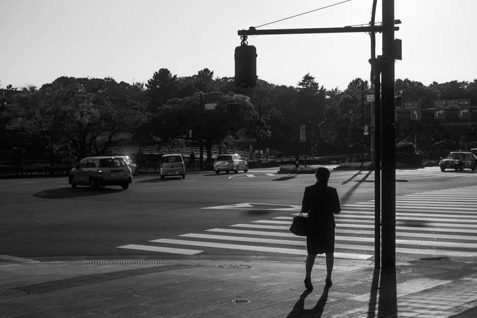 日本の東京の白黒の都市風景の中で道路を横断する人のシルエット。