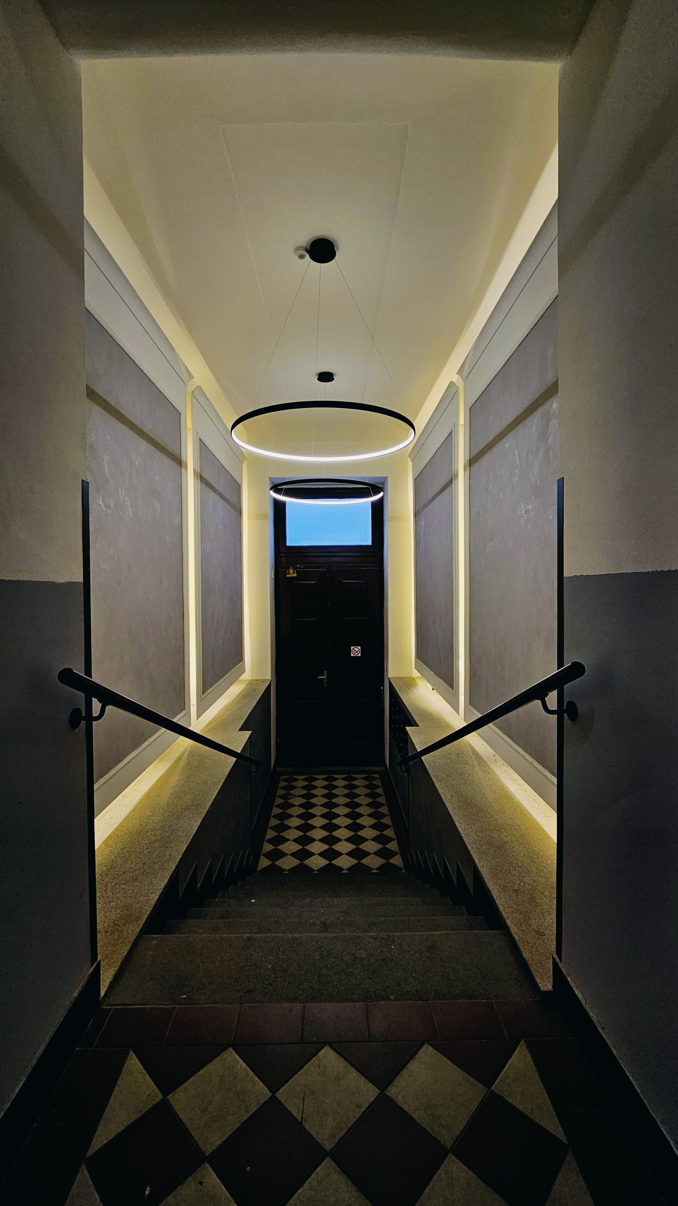 Stylish interior stairway with modern lighting and checkered flooring evokes a mysterious ambiance.