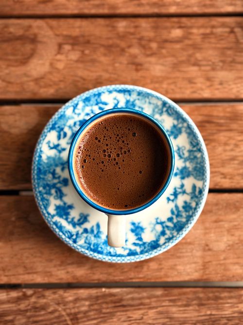 Free Aerial shot of rich Turkish coffee in a blue-patterned cup on wooden table. Stock Photo