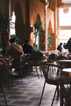 Stylish indoor cafe with people dining, adorned with plants and natural lighting.