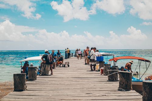 Free People enjoy a vibrant boardwalk by the sea under a bright blue sky, capturing a lively coastal scene. Stock Photo