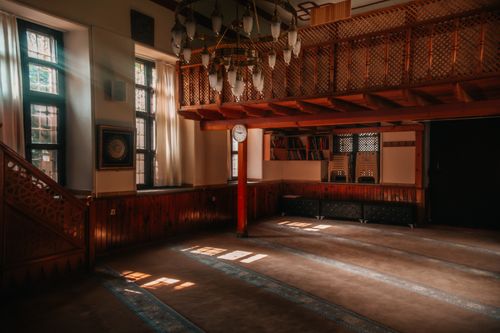 Free A serene, sunlit interior of a historic wooden mosque with intricate architecture. Stock Photo