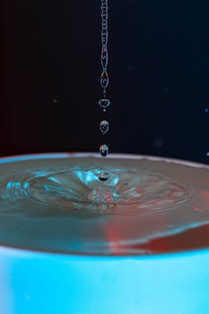 Captivating high-speed capture of water droplets creating ripples in vibrant lighting.