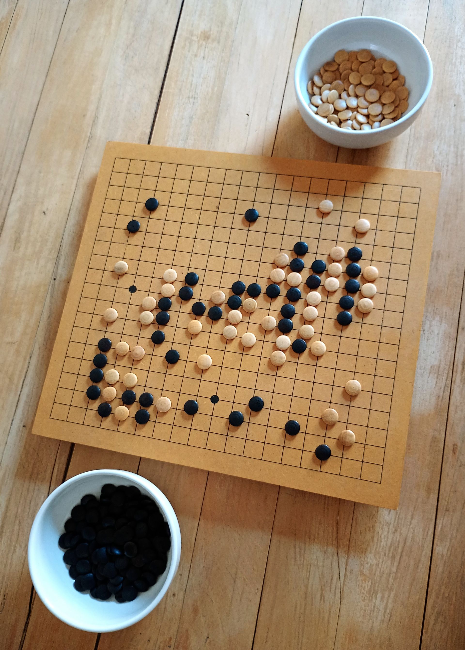 Aerial view of a traditional Go board with black and white stones arranged in strategic formations.