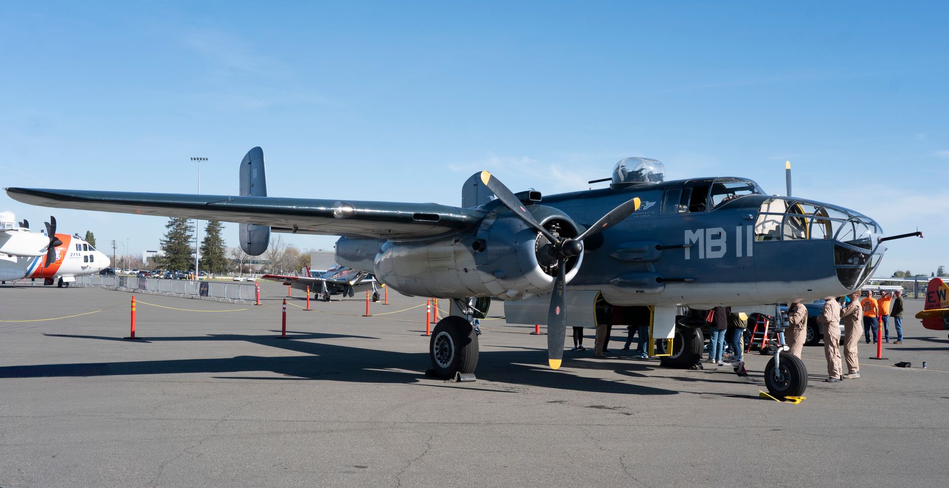 A vintage warplane displayed outdoors at an airshow, attracting visitors.