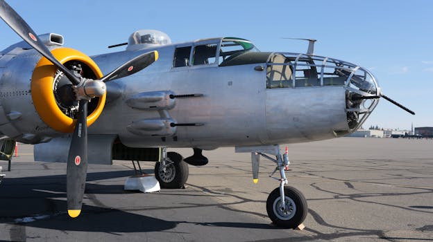 Close-up of a historic B-25 bomber parked on an airfield under a clear blue sky.