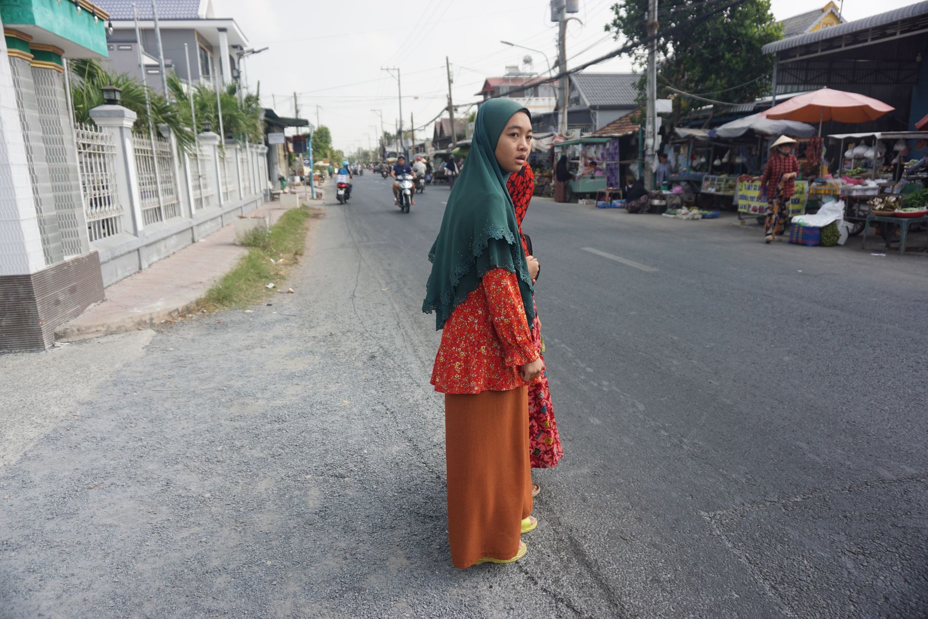 A woman in traditional attire crosses a street in Châu Đốc, capturing the essence of daily life in Vietnam.