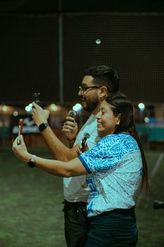 Two adults share a sportscasting moment at a nighttime soccer game.