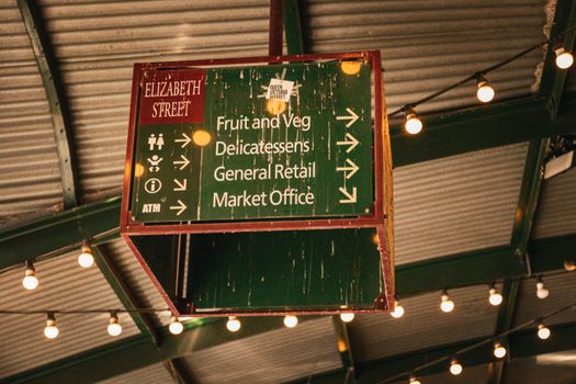 Vintage signage at Queen Victoria Market in Melbourne, highlighting stalls and shopping directions.