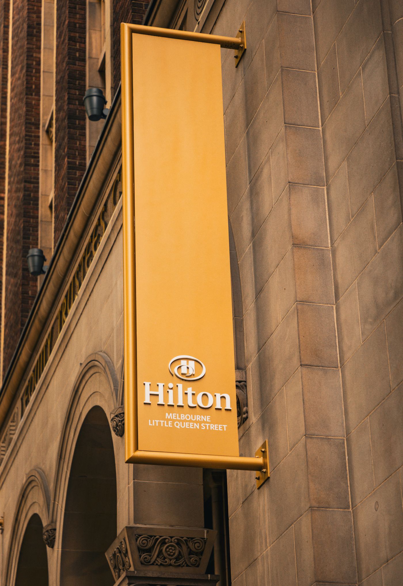 A vertical yellow Hilton Hotel sign on a historic building in Melbourne, Australia
