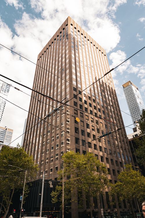 Free View of a tall office building against a cloudy sky in Melbourne, Australia, showcasing urban architecture. Stock Photo