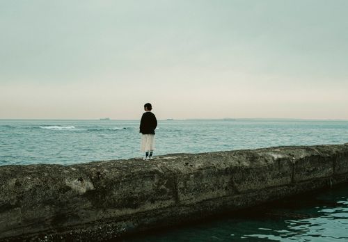 Free A contemplative woman stands on a pier, looking out at the tranquil sea in Chiba, Japan. Stock Photo