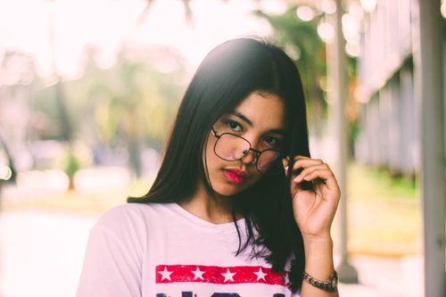 Free Portrait of a young woman in glasses with a stylish expression outdoors. Stock Photo