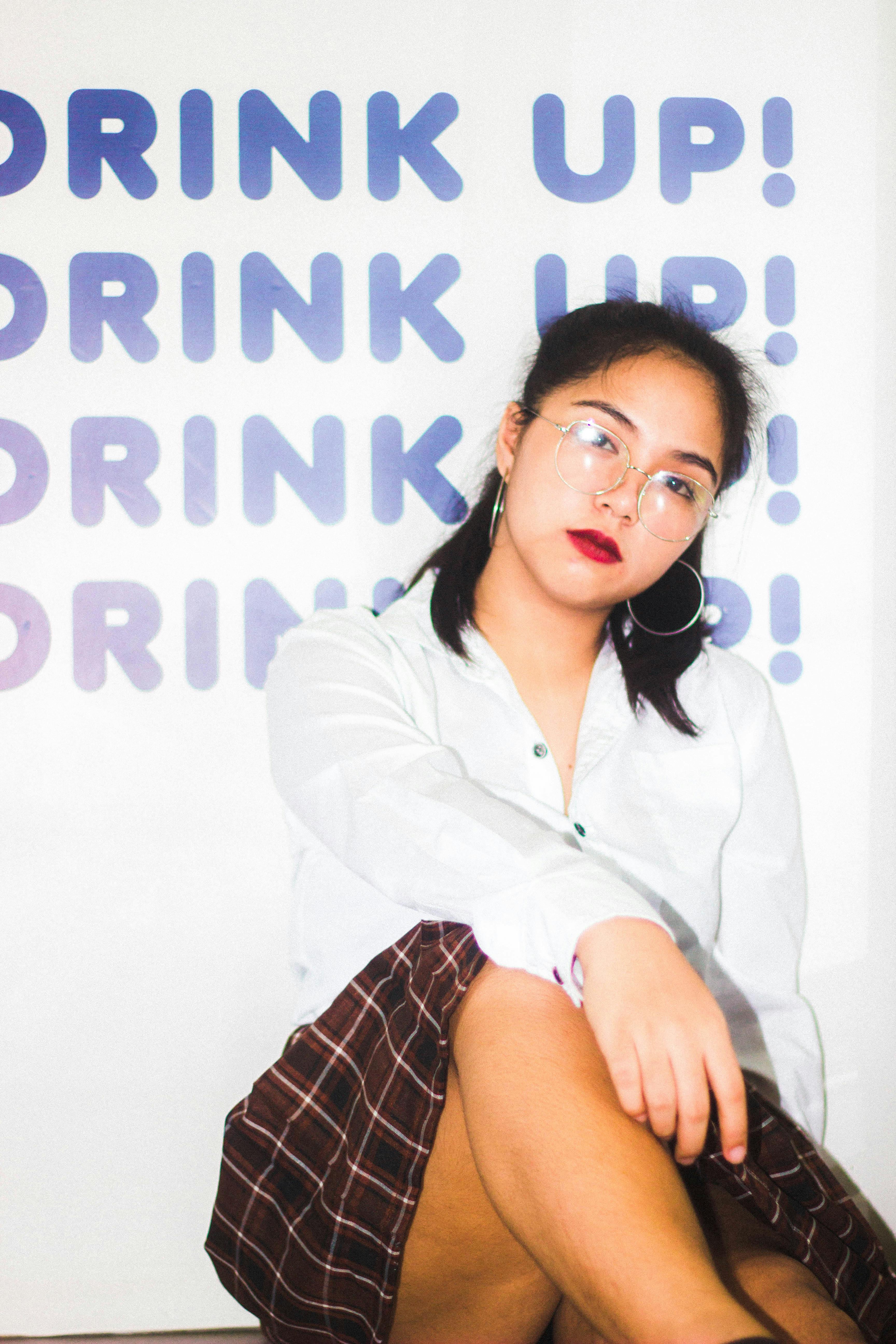 Portrait of a fashionable Asian woman posing indoors with glasses and bold red lipstick.
