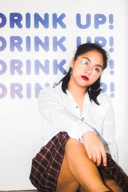 Portrait of a fashionable Asian woman posing indoors with glasses and bold red lipstick.