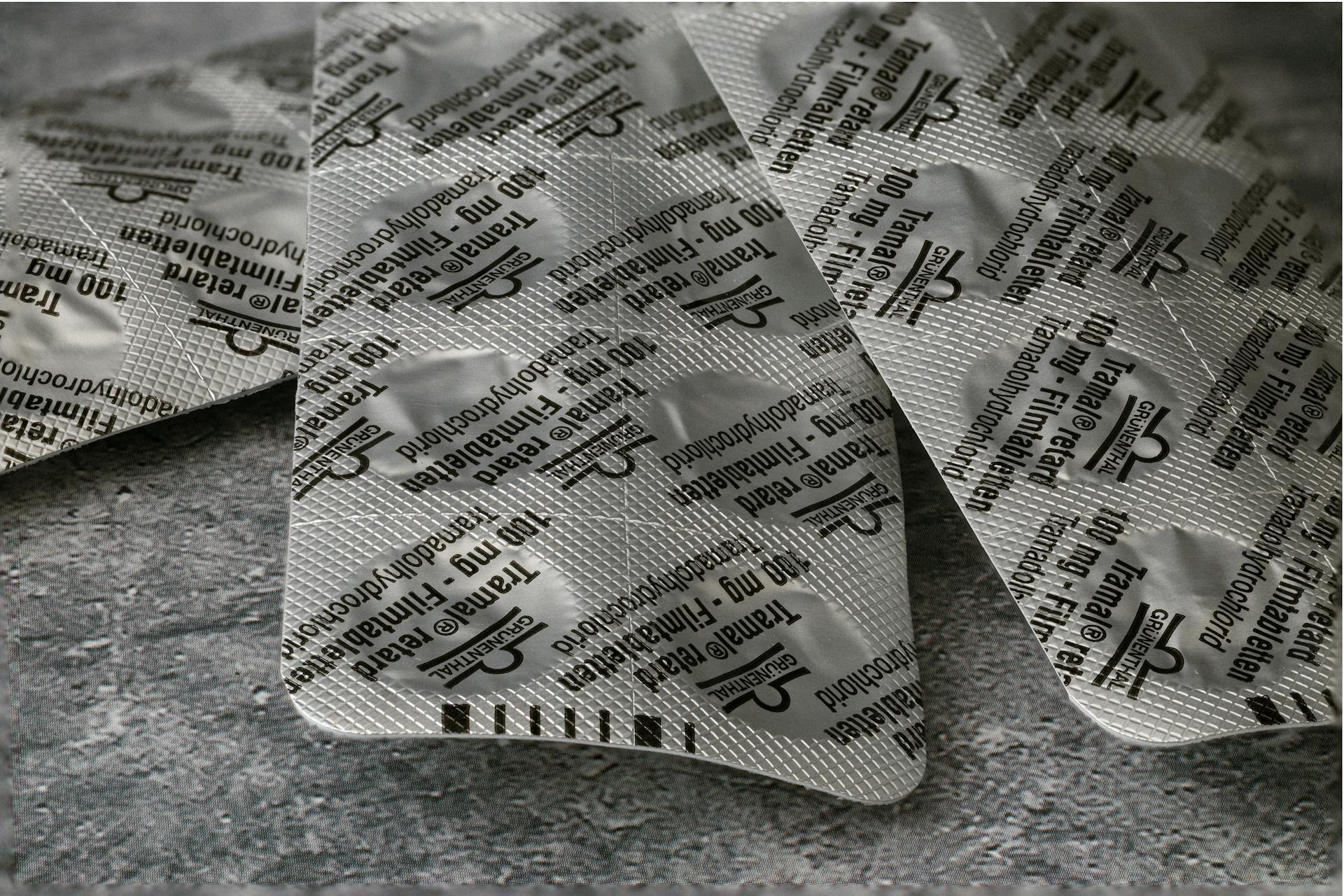 Close-up of Tramadol 100 mg blister pack on a textured concrete surface.