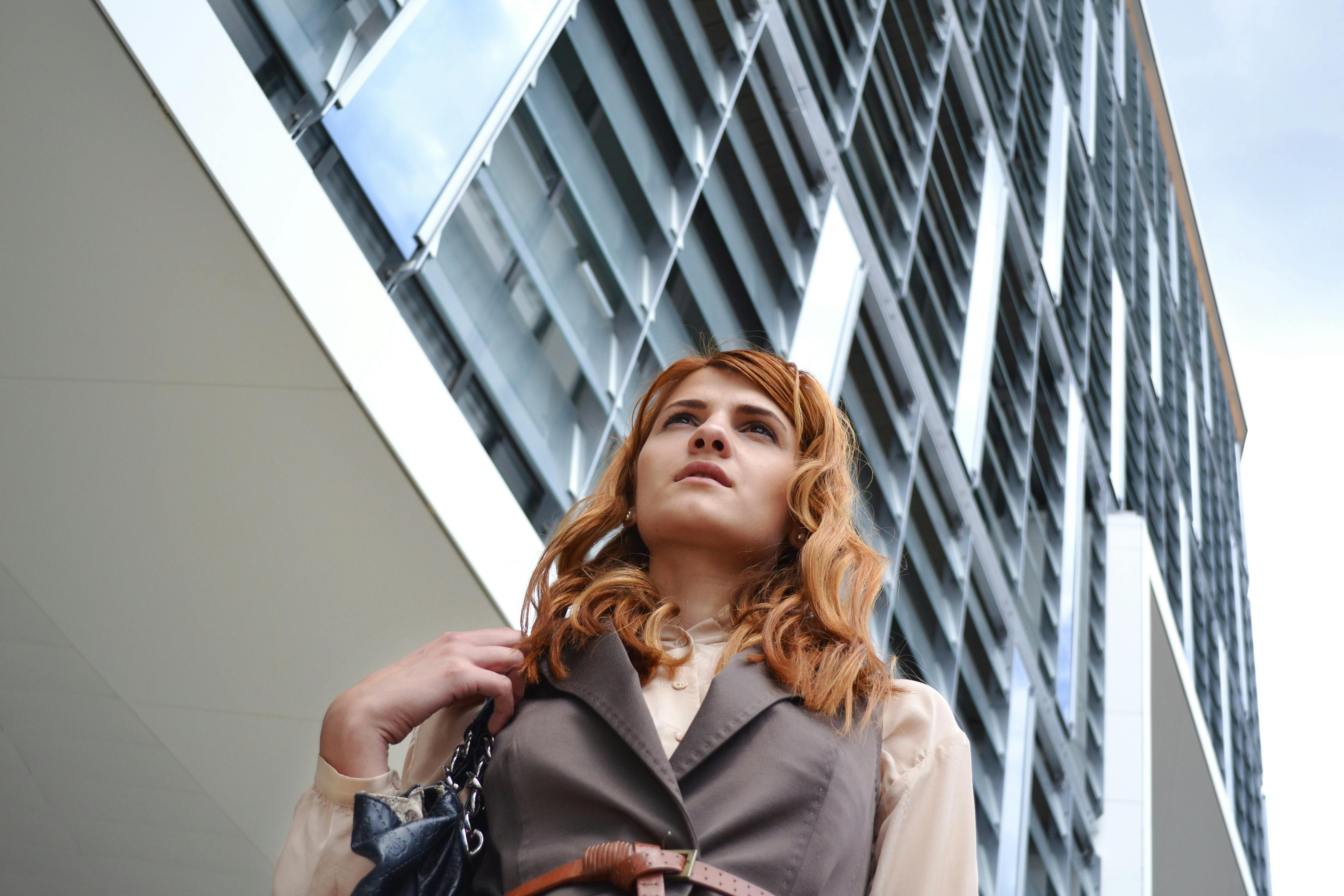 A fashionable young woman posing confidently in front of a modern building in the city.
